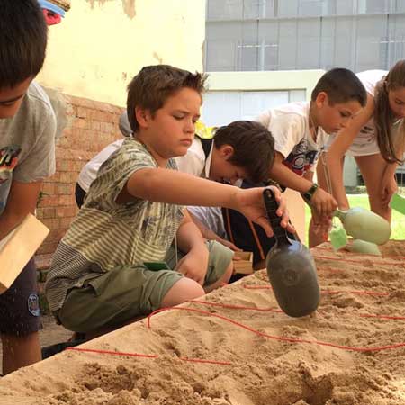 En la imagen aparece diferentes niños realizando una excavación en un banco de arena