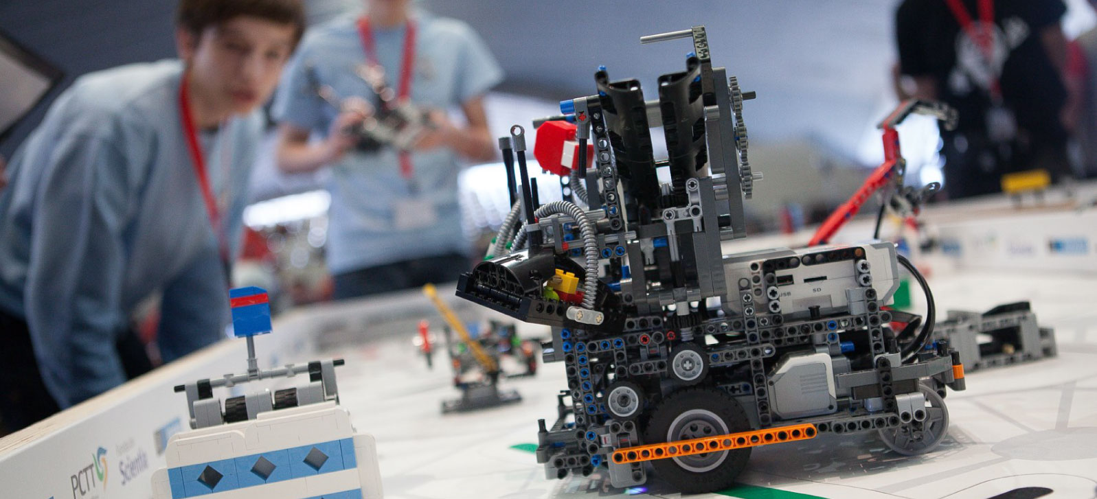 En la imagen aparece una niña con un robot creado a partir de piezas Lego