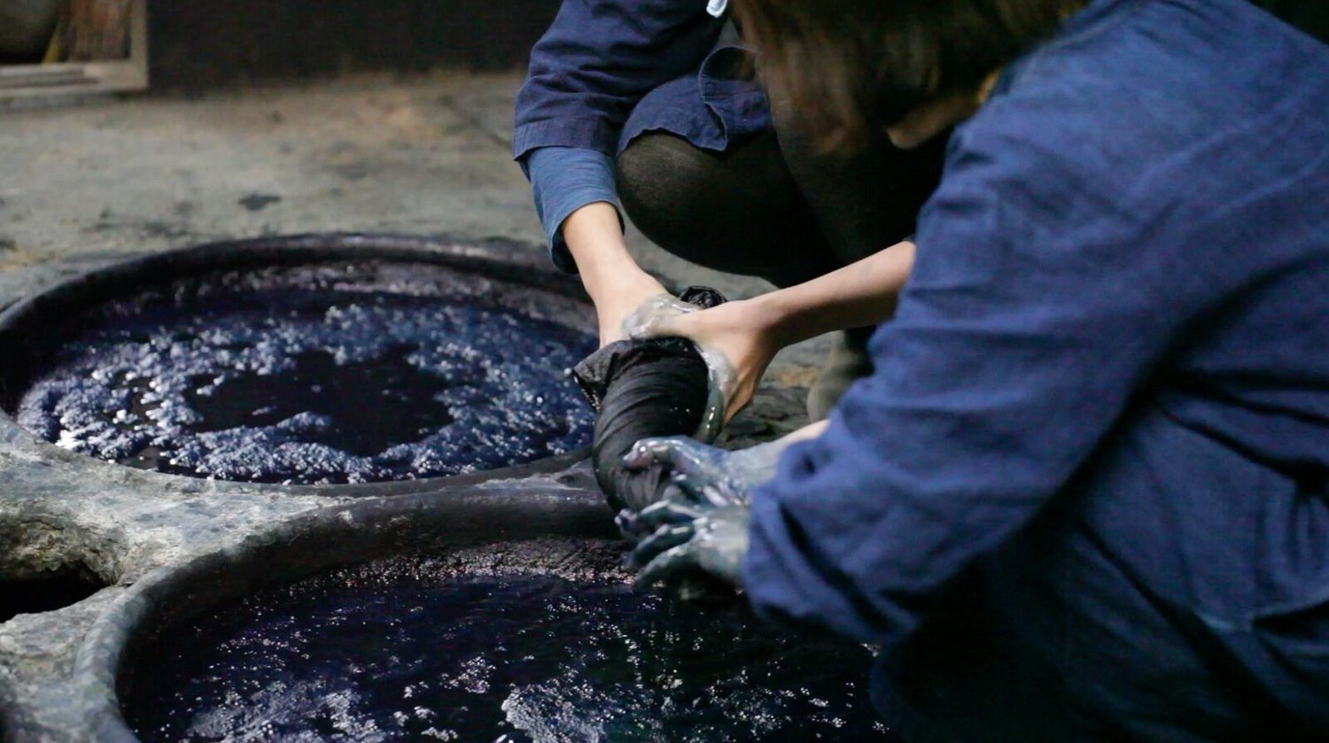 En la imagen aparece unas manos realizando tintes vegetales de color azul