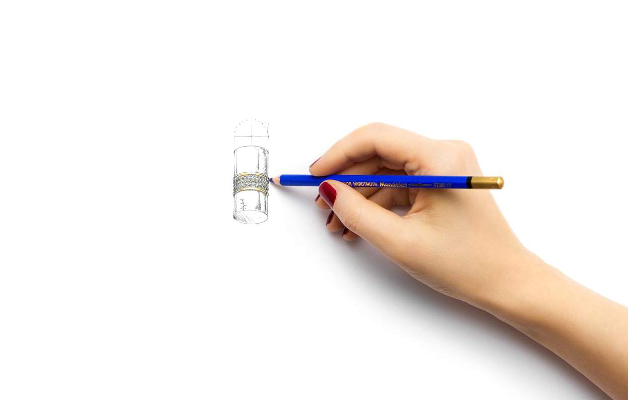 En la imagen aparece una mano dibujando una joya en lápiz carboncillo